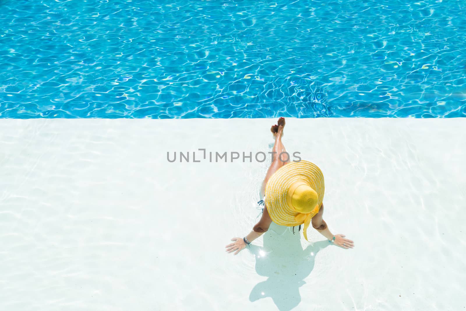 woman in a hat sitting on the edge of the pool by Netfalls