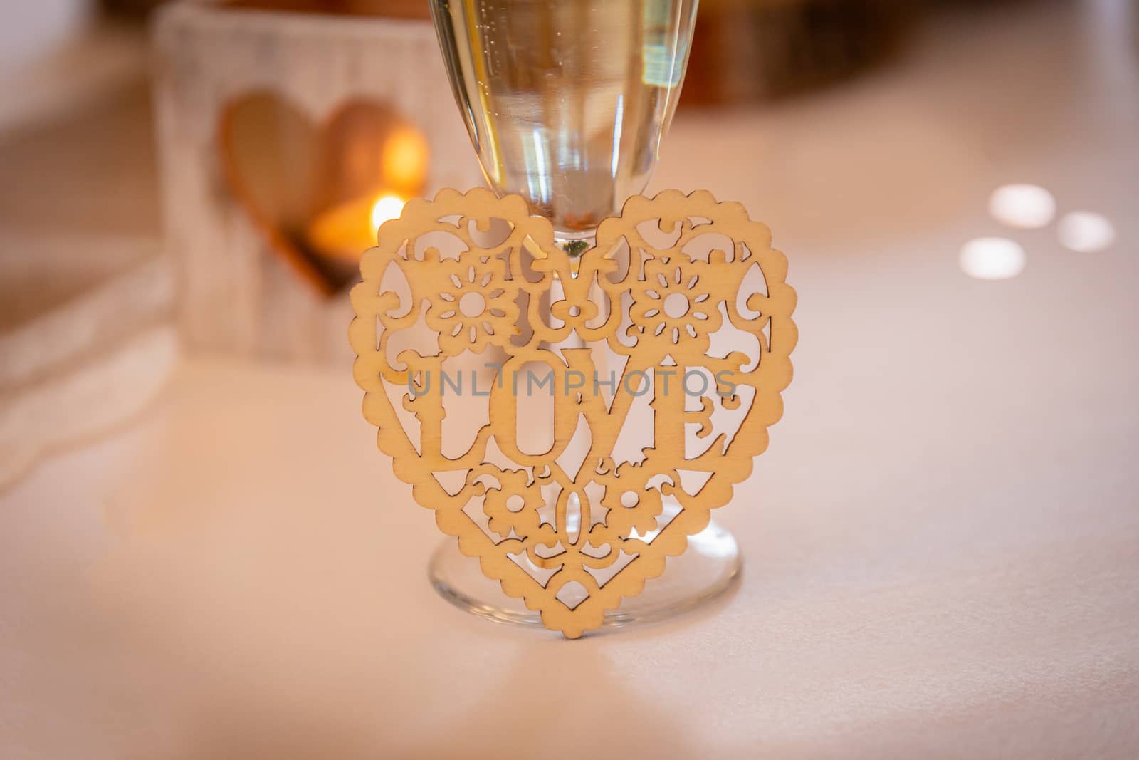 Love concept.  Champagne glass with love text and heart shapes on accessories in a wedding setting