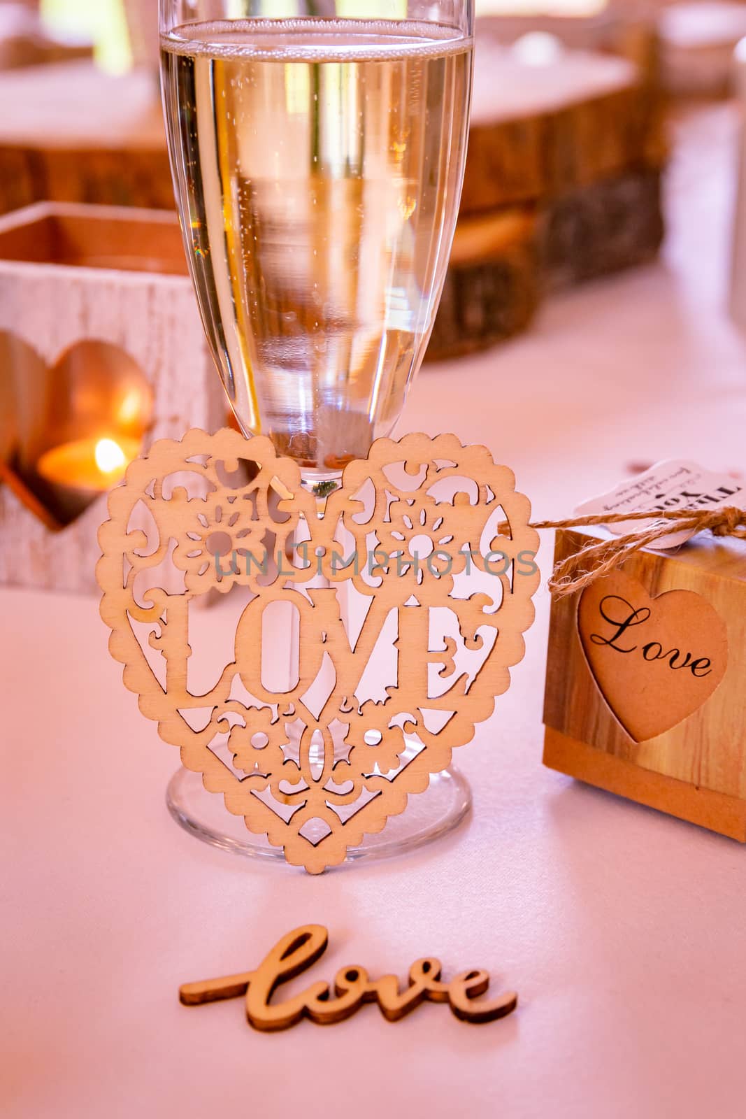 Love concept.  Champagne glass with love text and heart shapes on accessories in a wedding setting