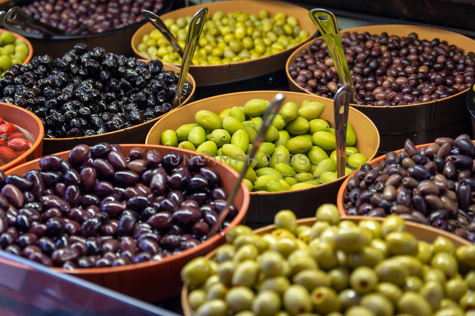 Bowls of green and black olives on display on a stall