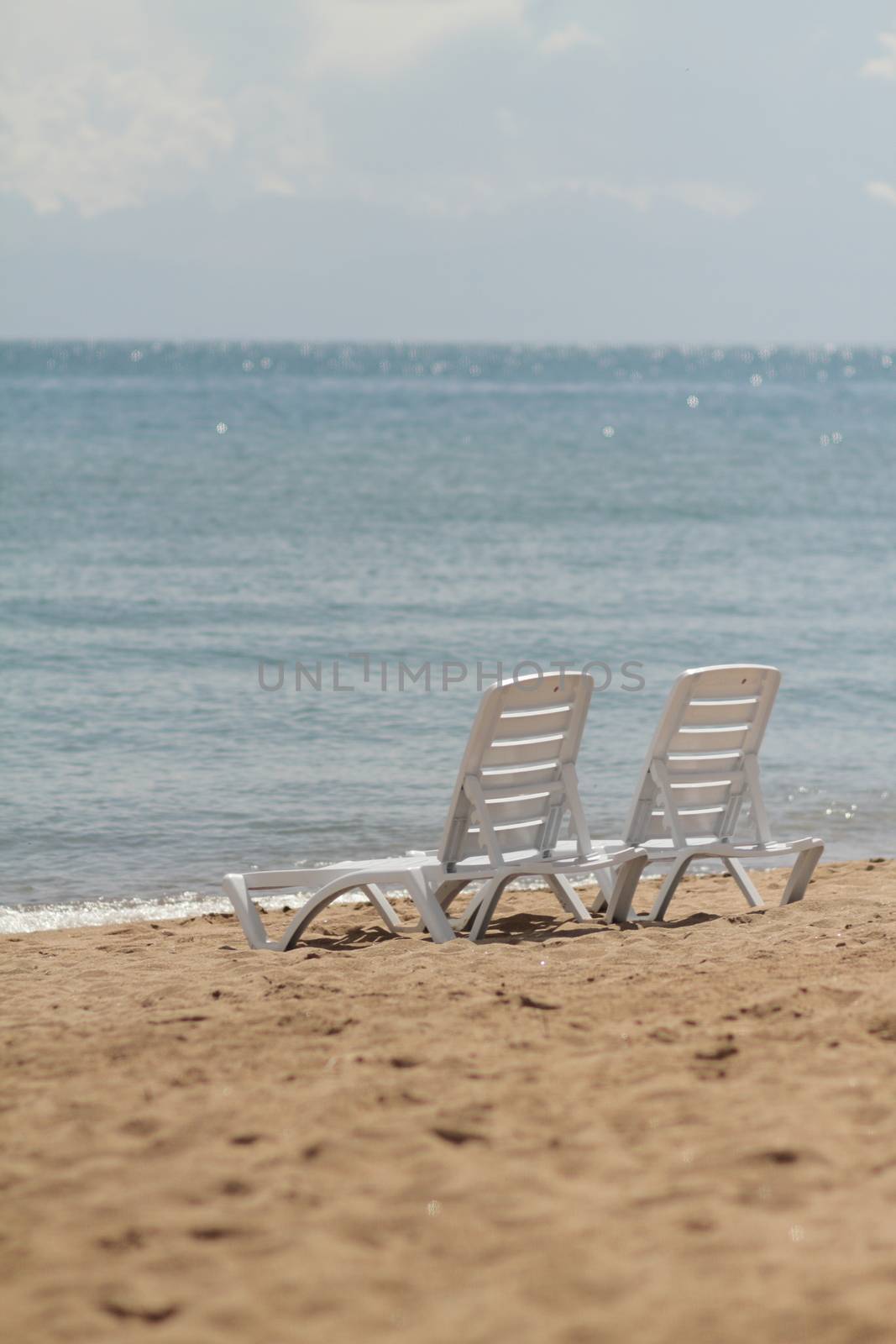 Deck chair in the sand on the shore. Relax, relaxation on the beach. Blue water in the ocean sea. Travel to the sea of the island. Holidays at sea. Air tourism. High quality photo