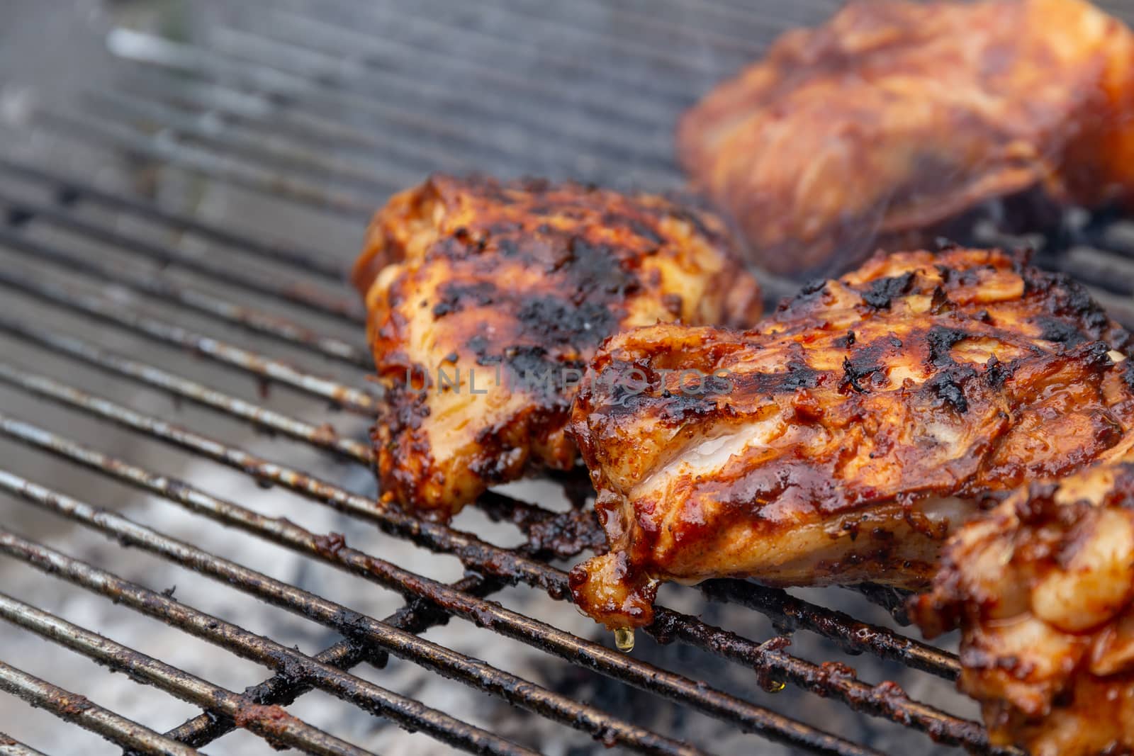 Marinated chicken pieces being cooked on a barbecue