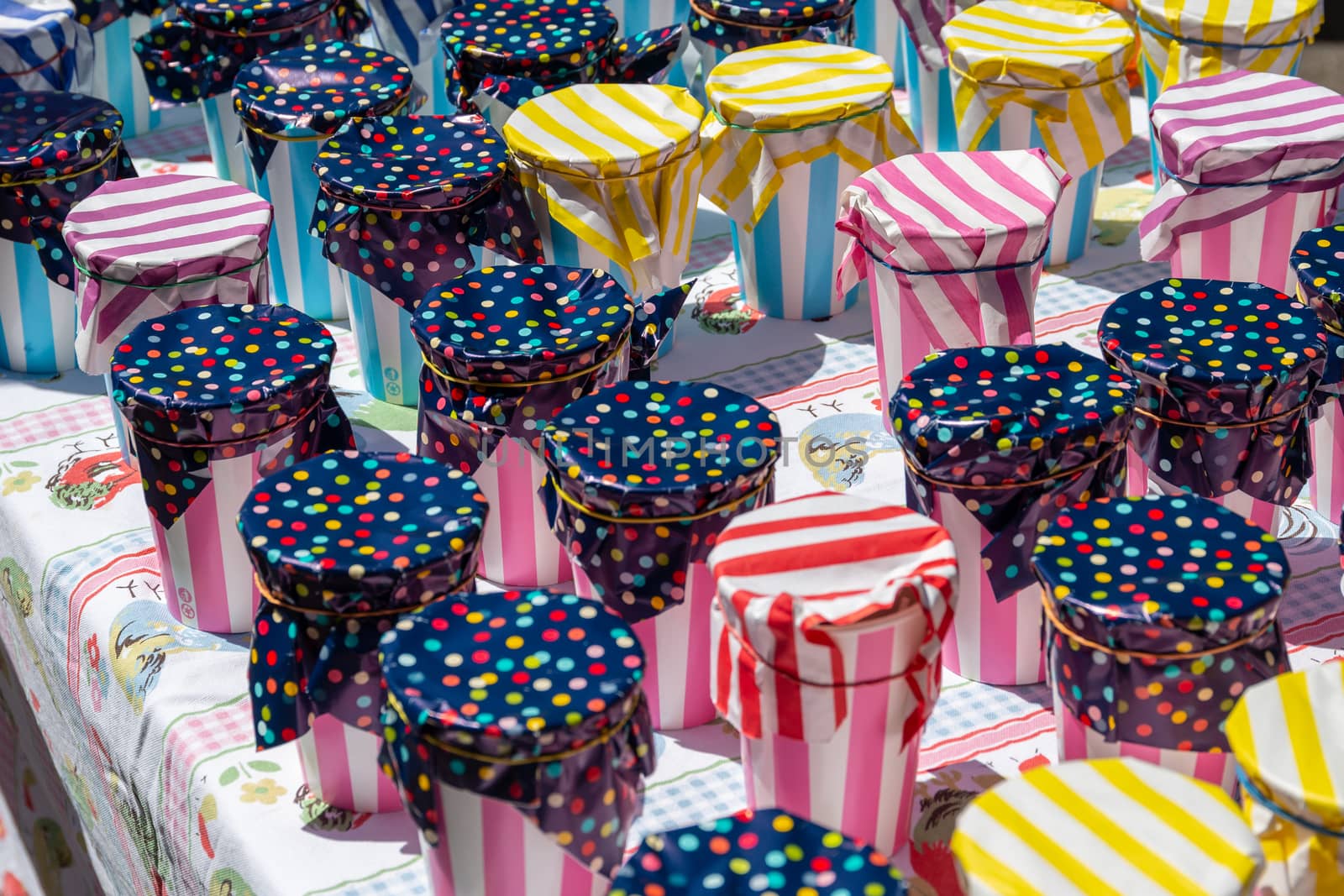 An assortment of colorful containers, on a table, covered with bright colorful paper and secured with elastic bands