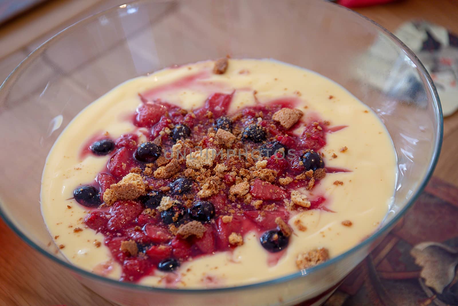 Homemade trifle with custard, strawberries, blueberries and crumbled biscuits