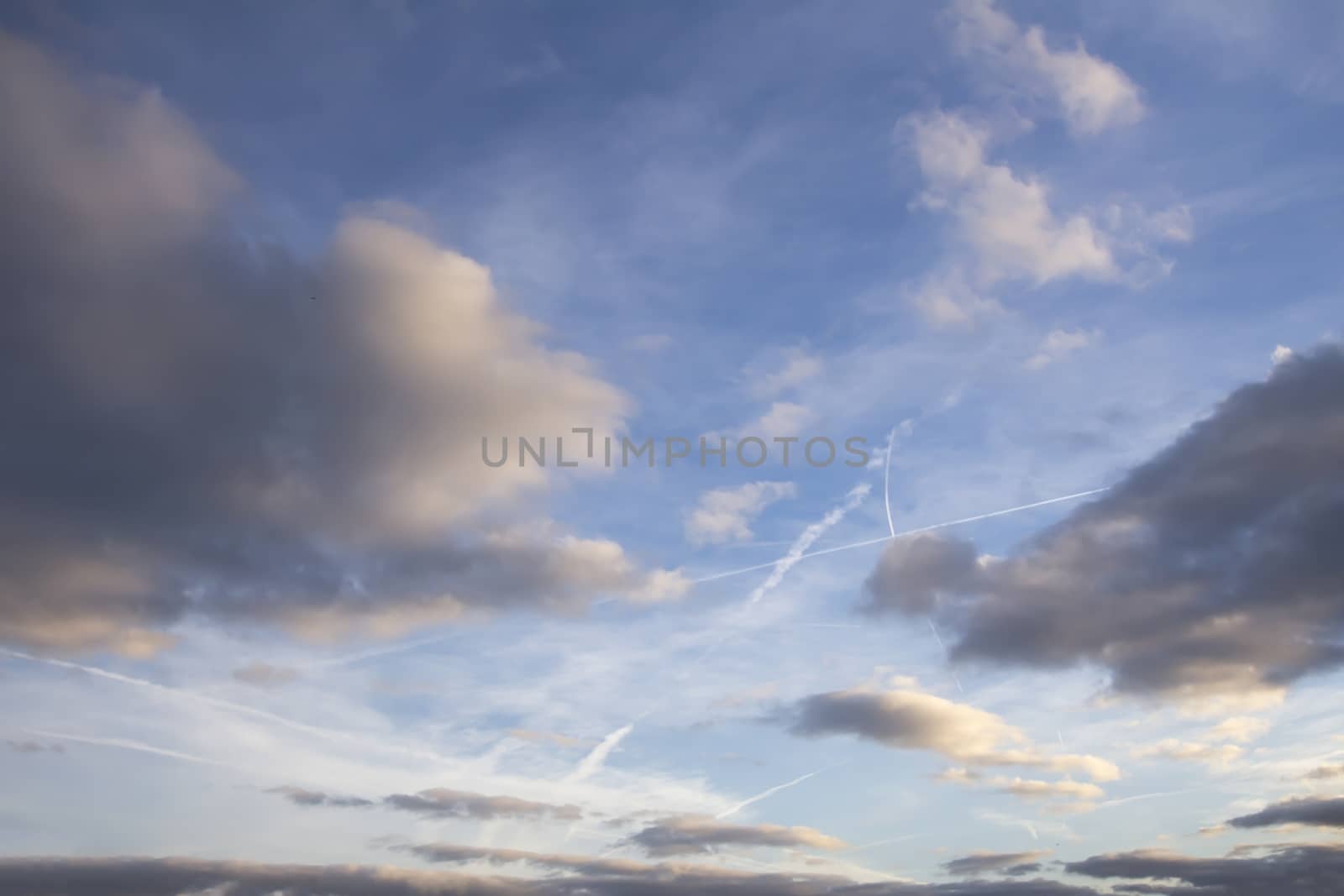 Dark clouds and aeroplane trails in a blue sky