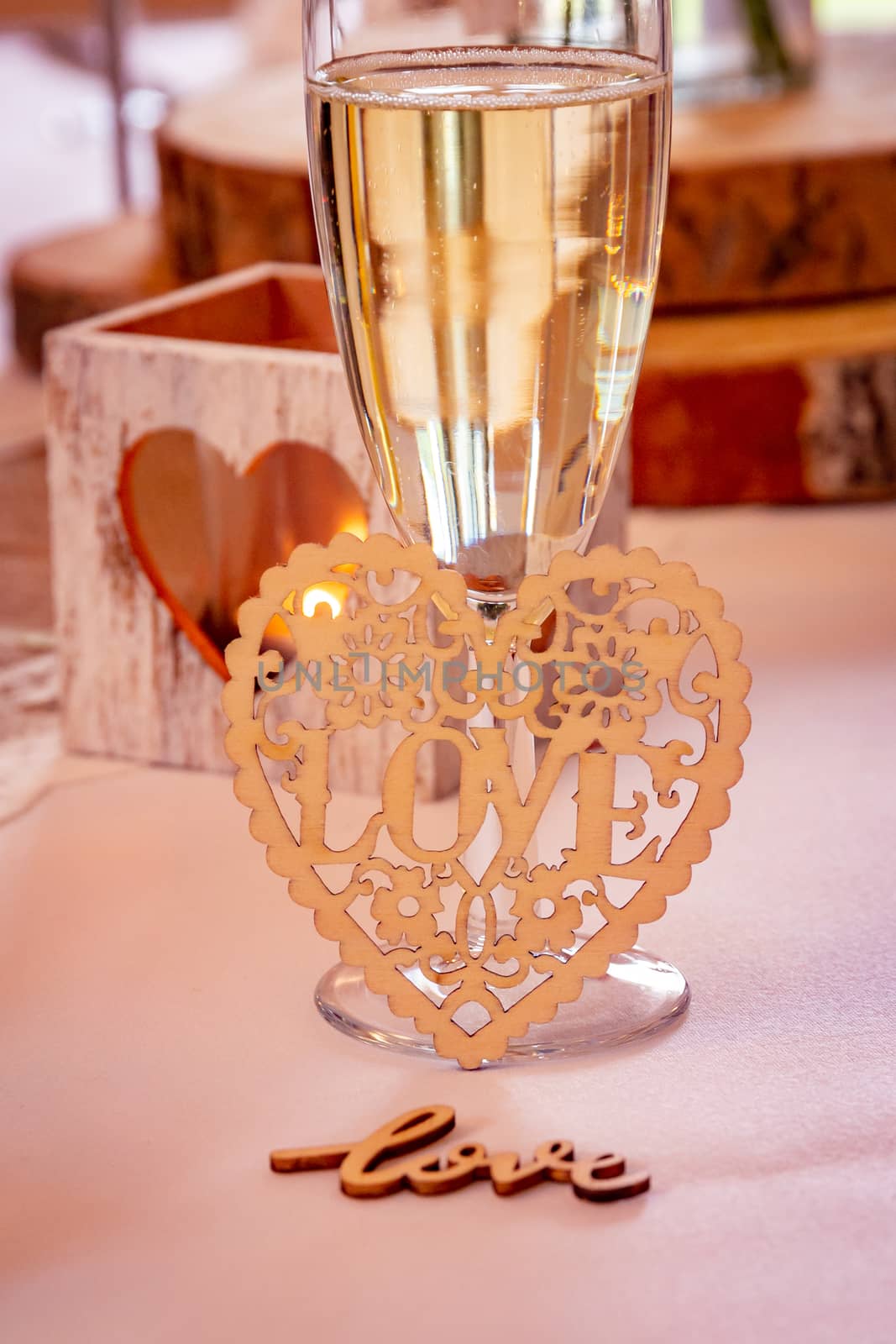 Love concept.  Champagne glass with love text and heart shapes on accessories in a wedding setting