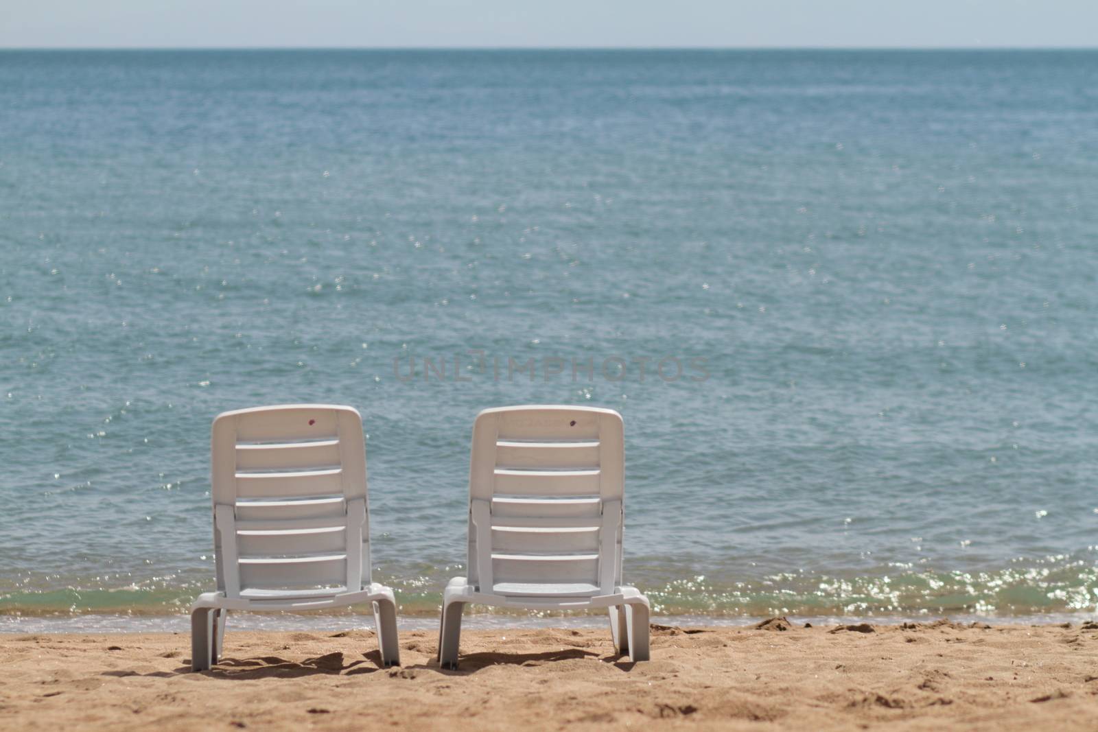 Deck chair in the sand on the shore. Relax, relaxation on the beach. Blue water in the ocean sea. by selinsmo