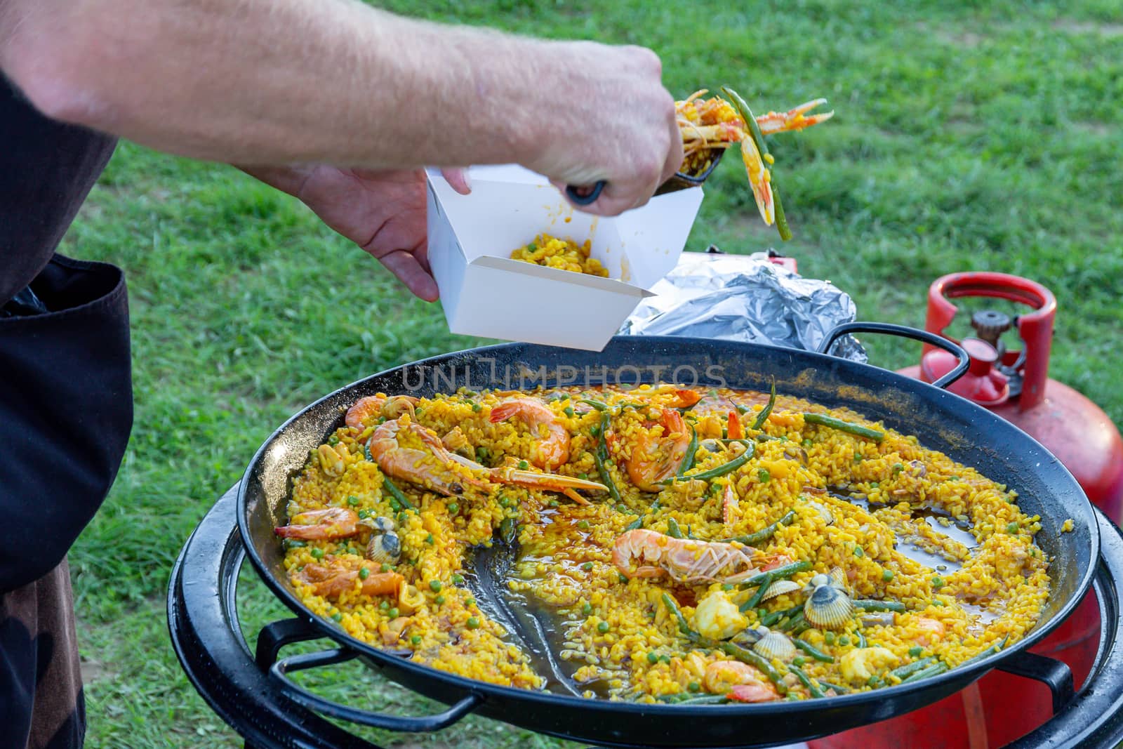 A large pan of seafood paella being served outdoors