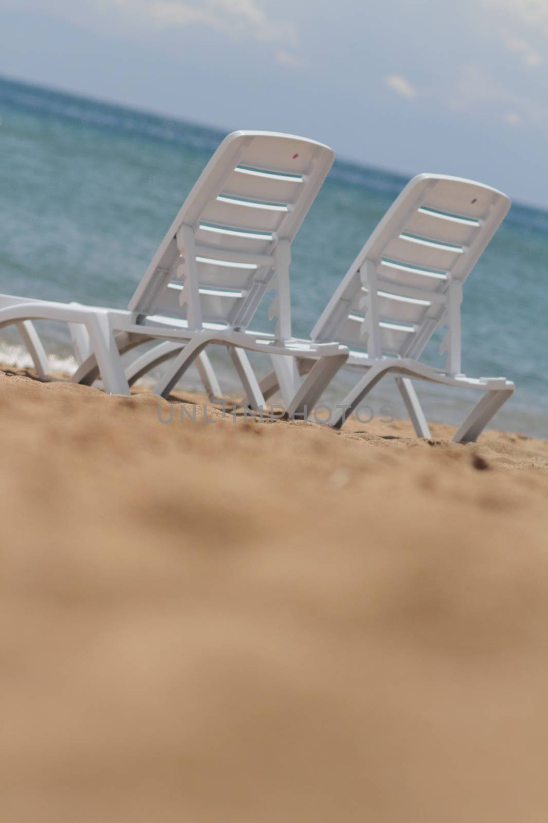 Deck chair in the sand on the shore. Relax, relaxation on the beach. Blue water in the ocean sea. by selinsmo