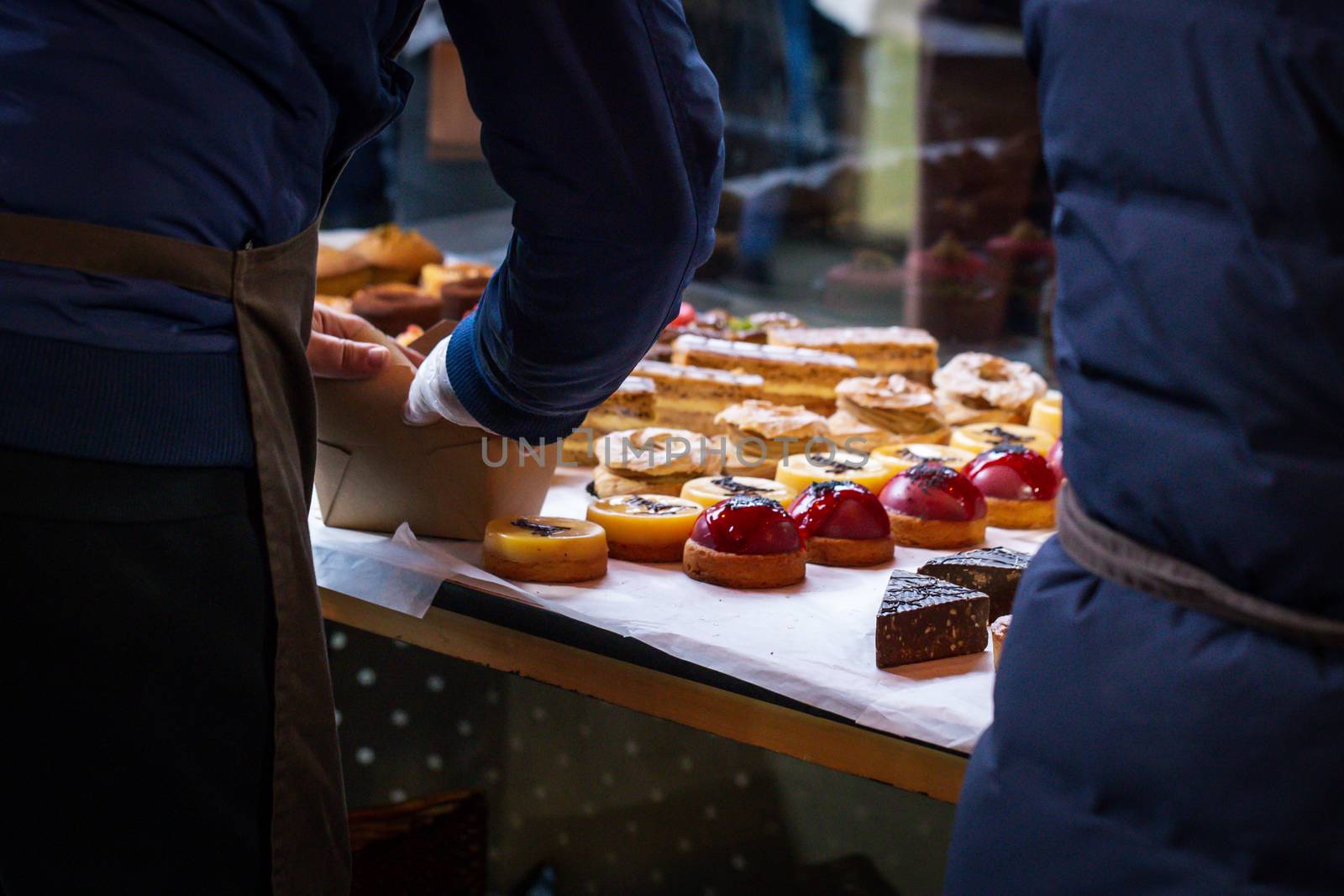 Vendors selling cakes and desserts on a market stall by magicbones