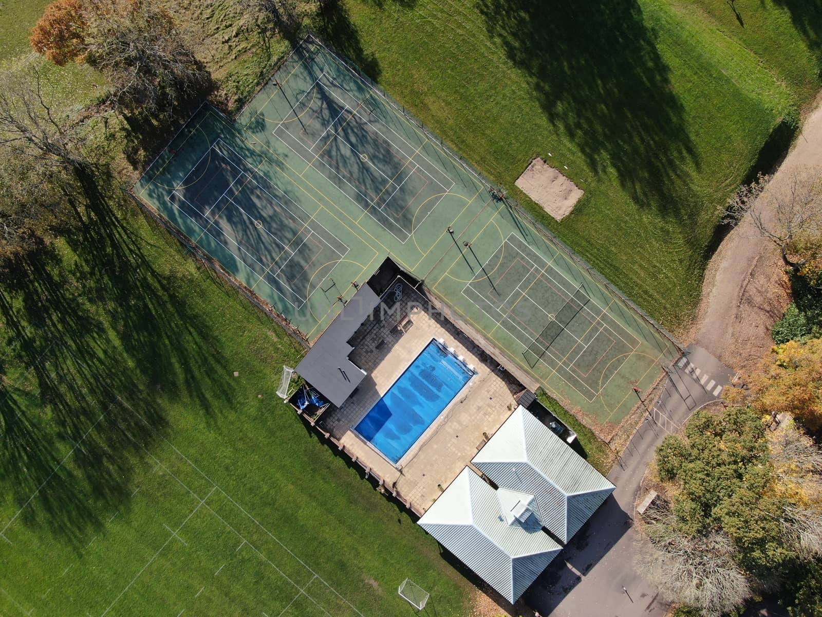 Aerial view of three tennis courts and and an open air swimming pool