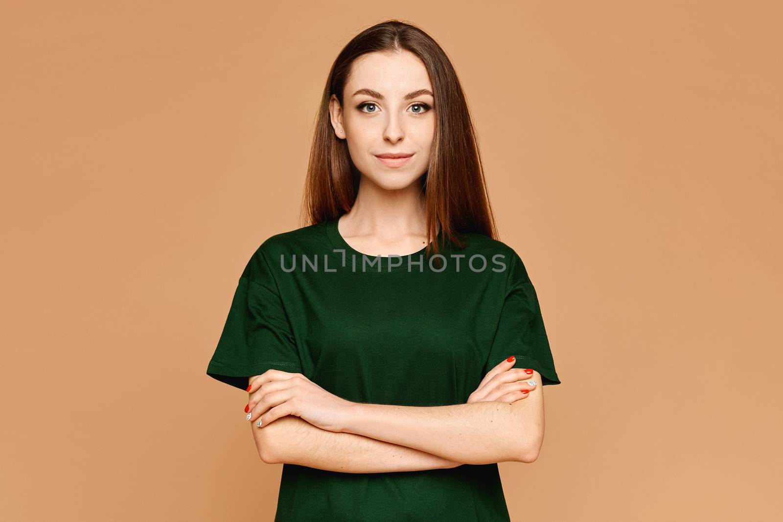 Young model girl with folded hands in a blank t-shirt isolated over the beige background.