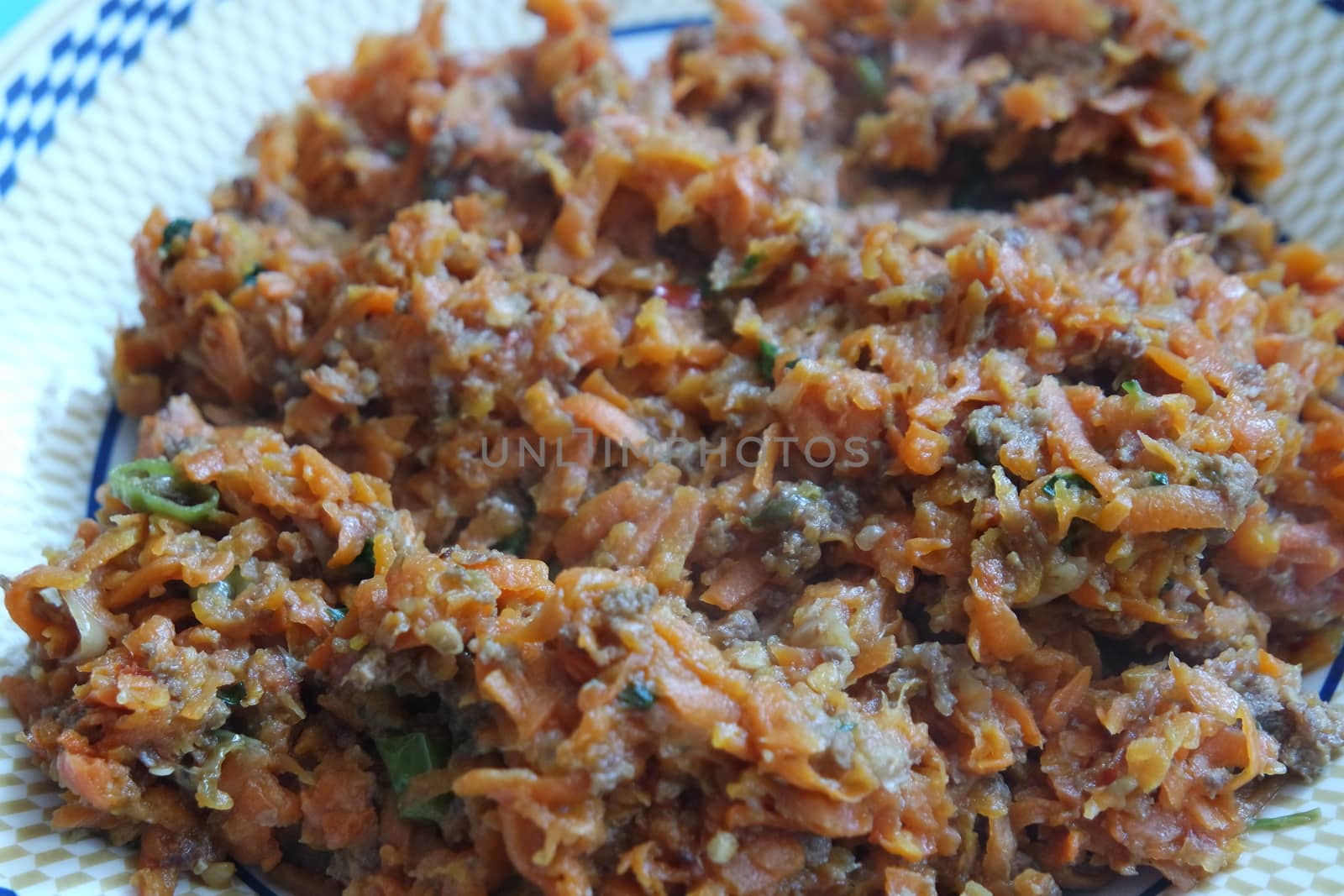 Top closeup view of a homemade dish made from carrot and vegetables served in a ceramic plate.