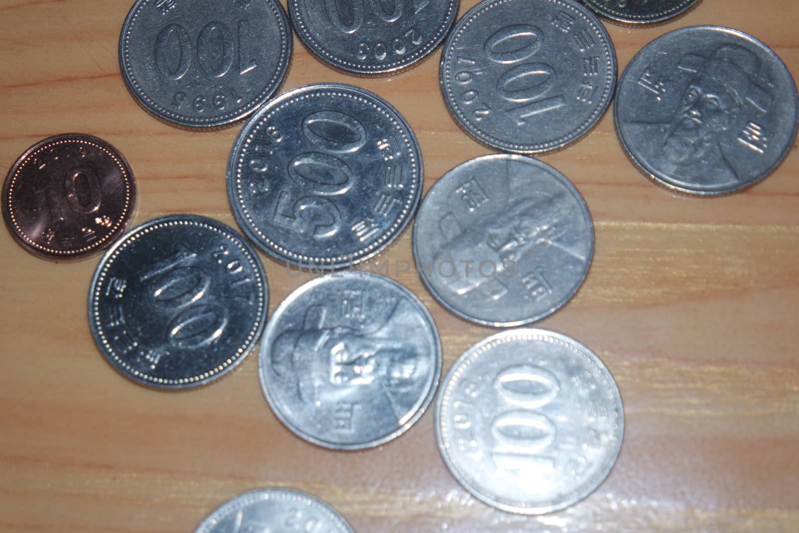 Korean won coin scattered over a wooden floor by Photochowk