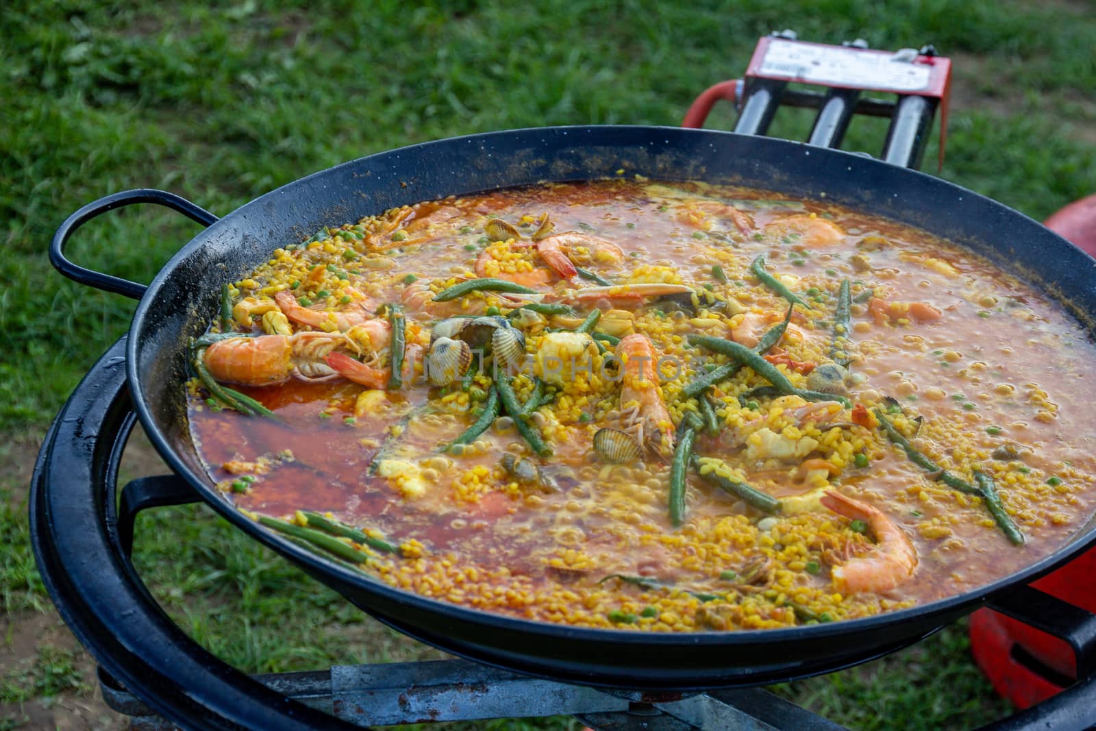 A large pan of seafood paella being prepared outdoors