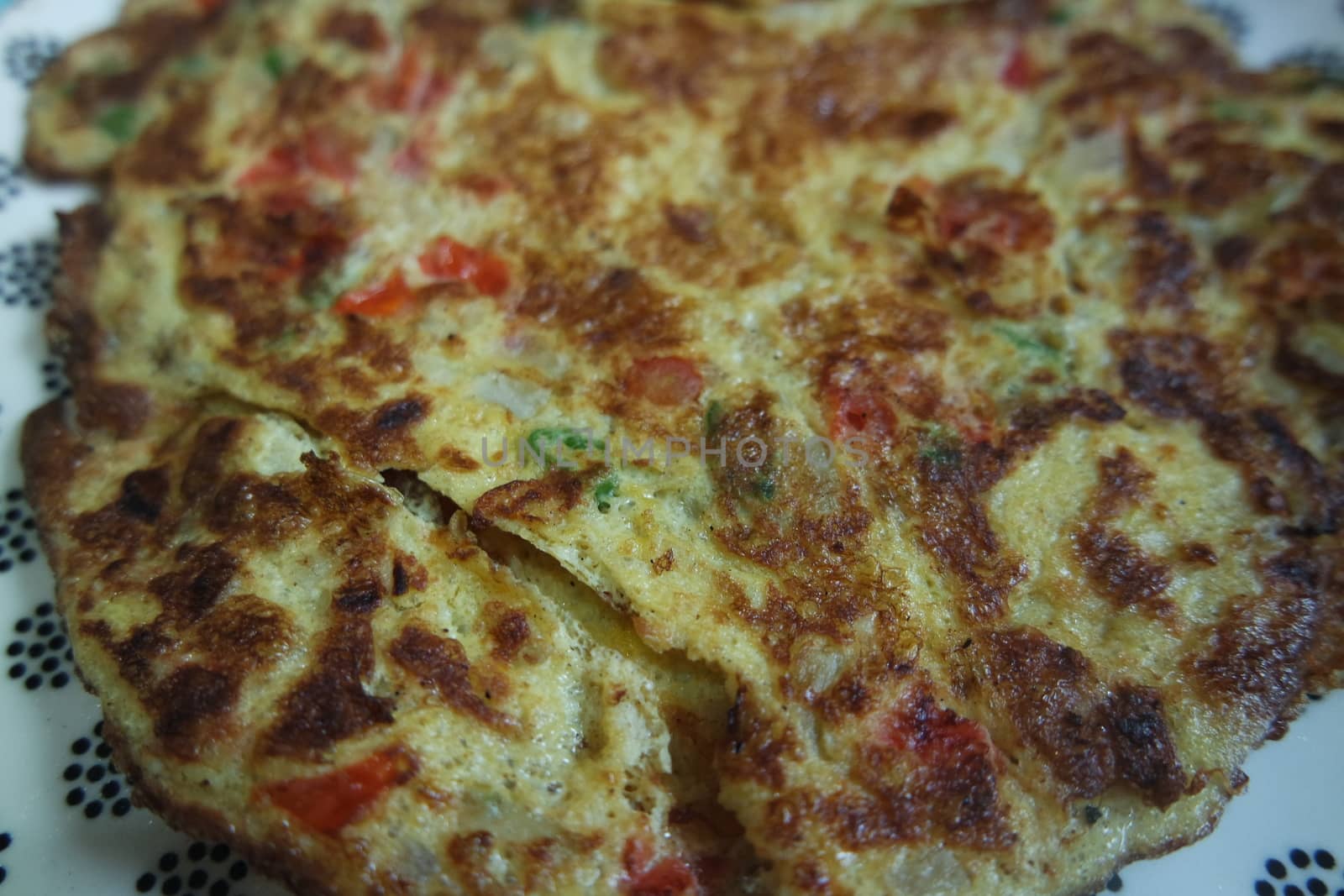 Close-up view with selective focus of egg omelet with peppers and spices sprinkled
