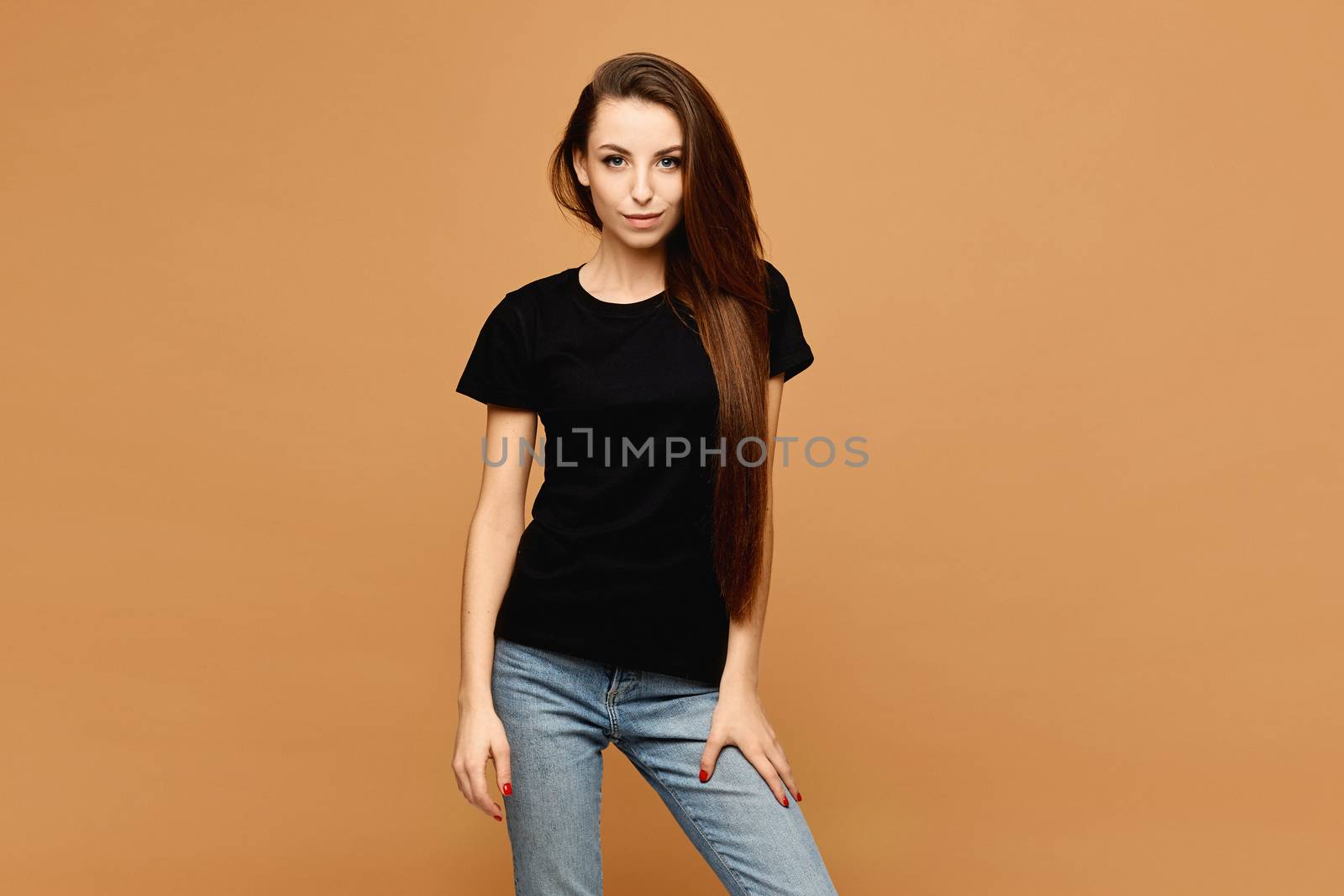 Young smiling woman with slim perfect body in a black t-shirt at the beige background, isolated. Sale advertisement mockup.