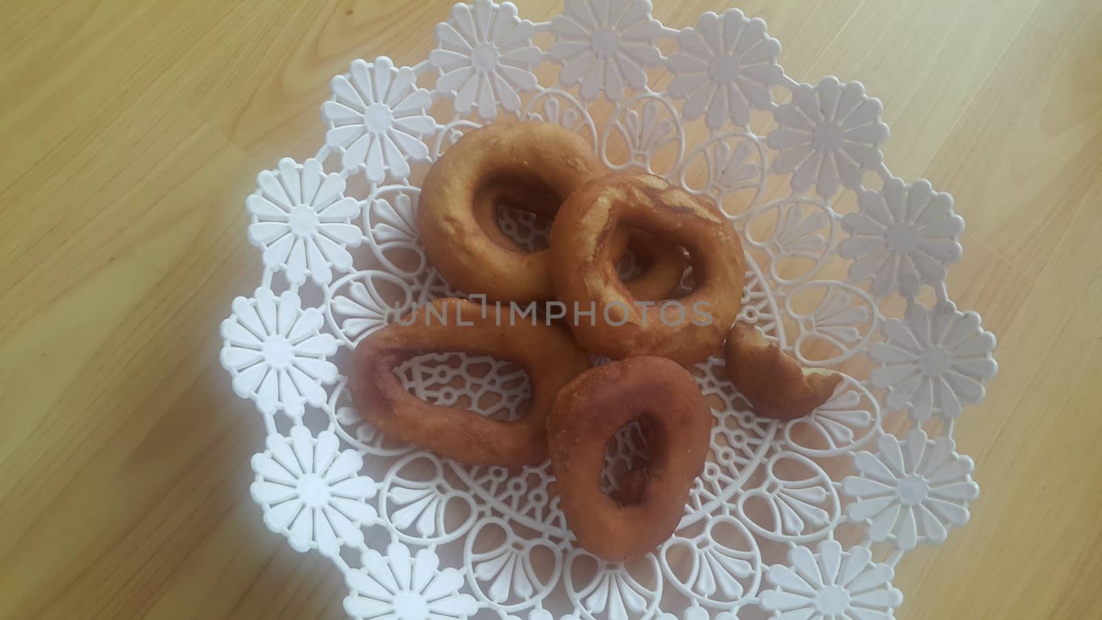 Closeup view of a set of freshly prepared donuts served on white changair. Donuts are placed in a changair over wooden floor