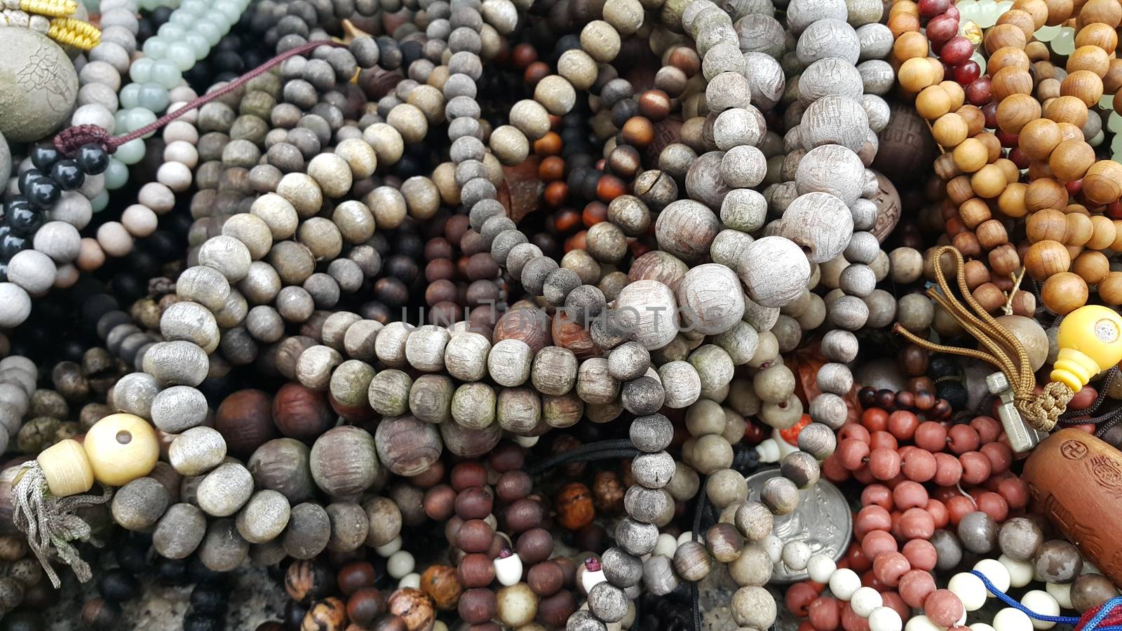 Beautiful wooden prayer beads or rosary placed over fabric background by Photochowk