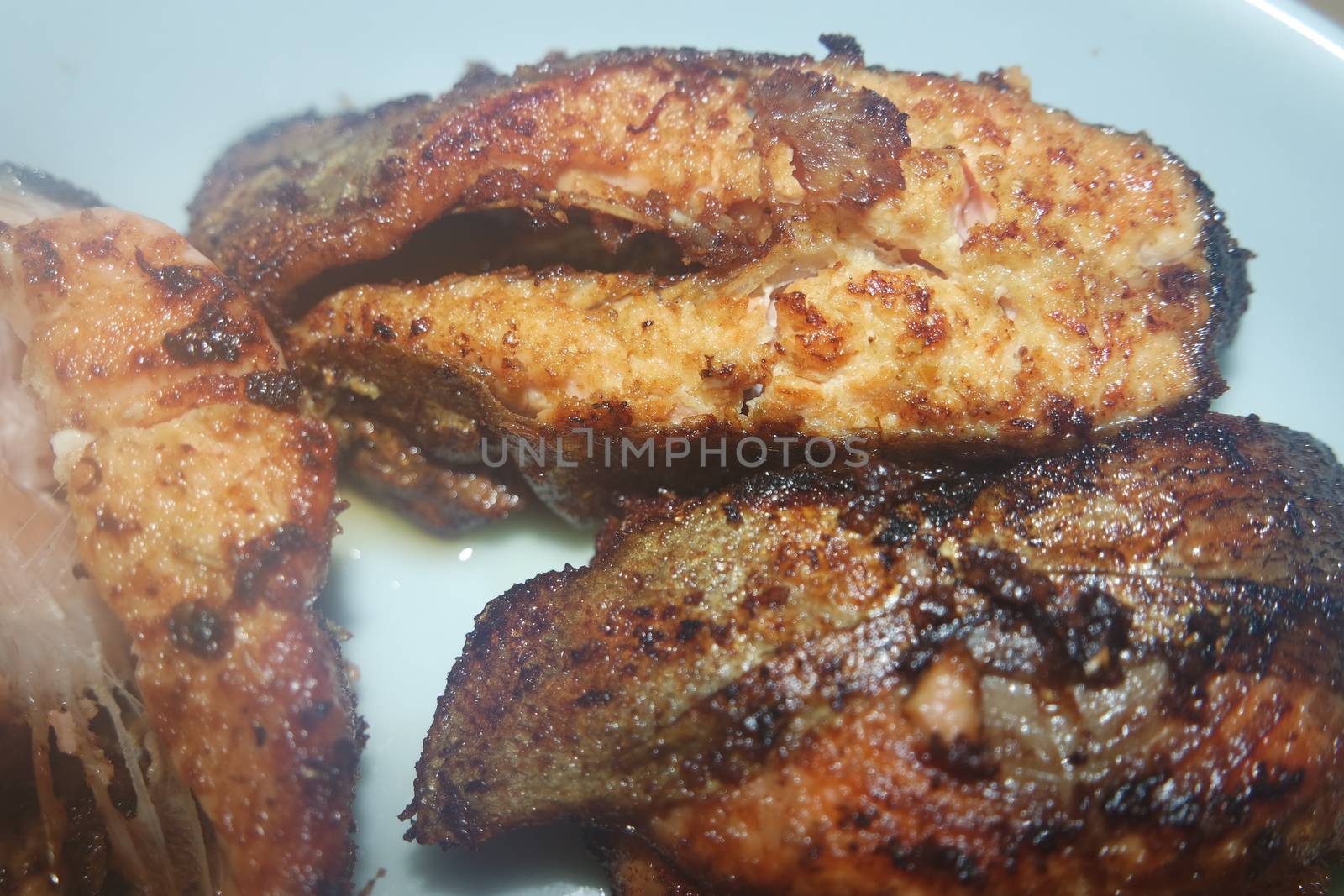 Spicy and crunchy barbecue of fried fish fillet on a white background. Homemade grilled trout fish steaks for health nourishments.