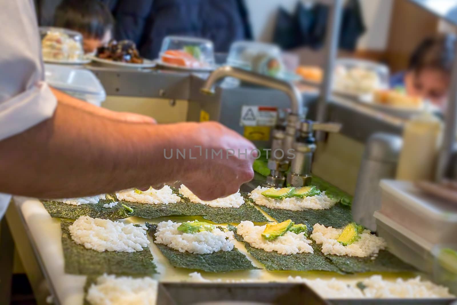 A sushi chef preparing Uramaki with avocado and salmon