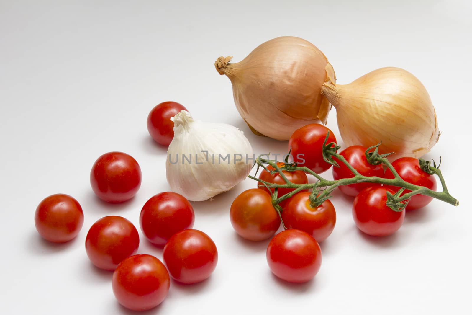 An arrangement of onons, tomatoes and garlic on a white background