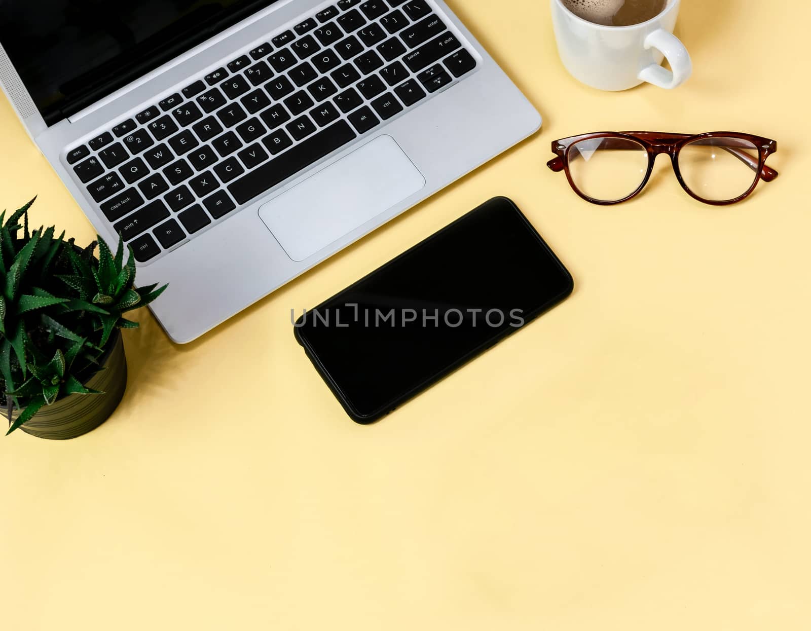 Laptop placed on a yellow table background of business working place with cup coffee, Empty workspace