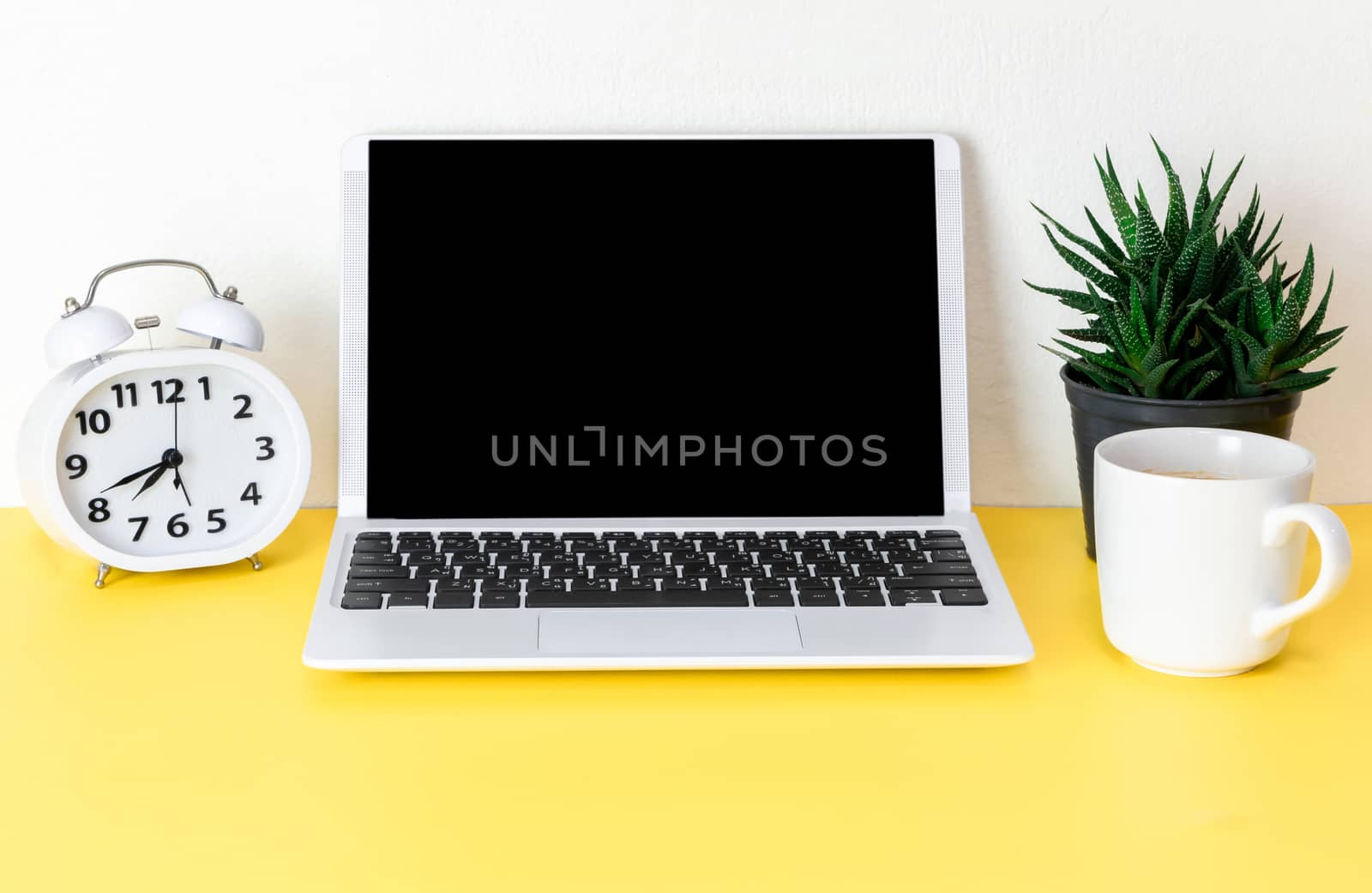 Laptop placed on a yellow table background of business working place with cup coffee, Empty workspace