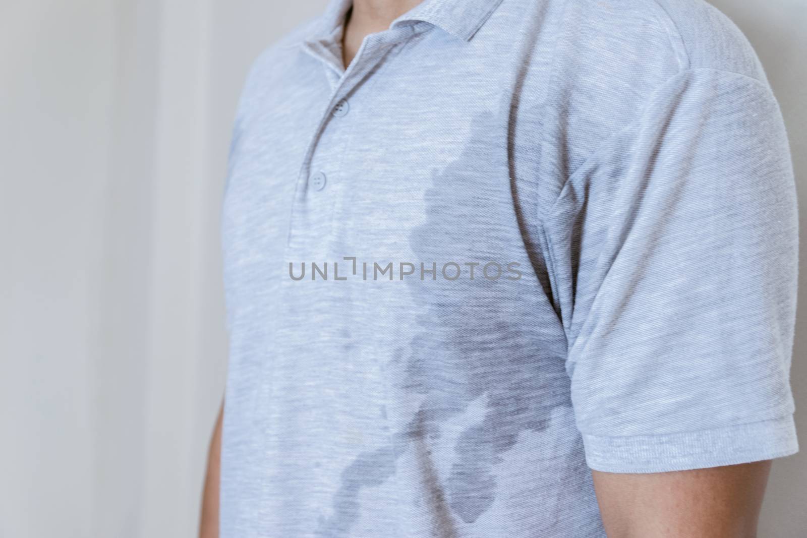 Man with sweat stain on clothes against, using deodorant by sompongtom