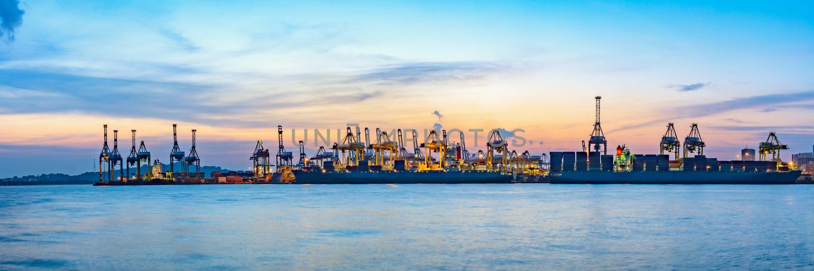 Freighter ship loading cargo at loading dock on twilight time. Singapore, south east asia.