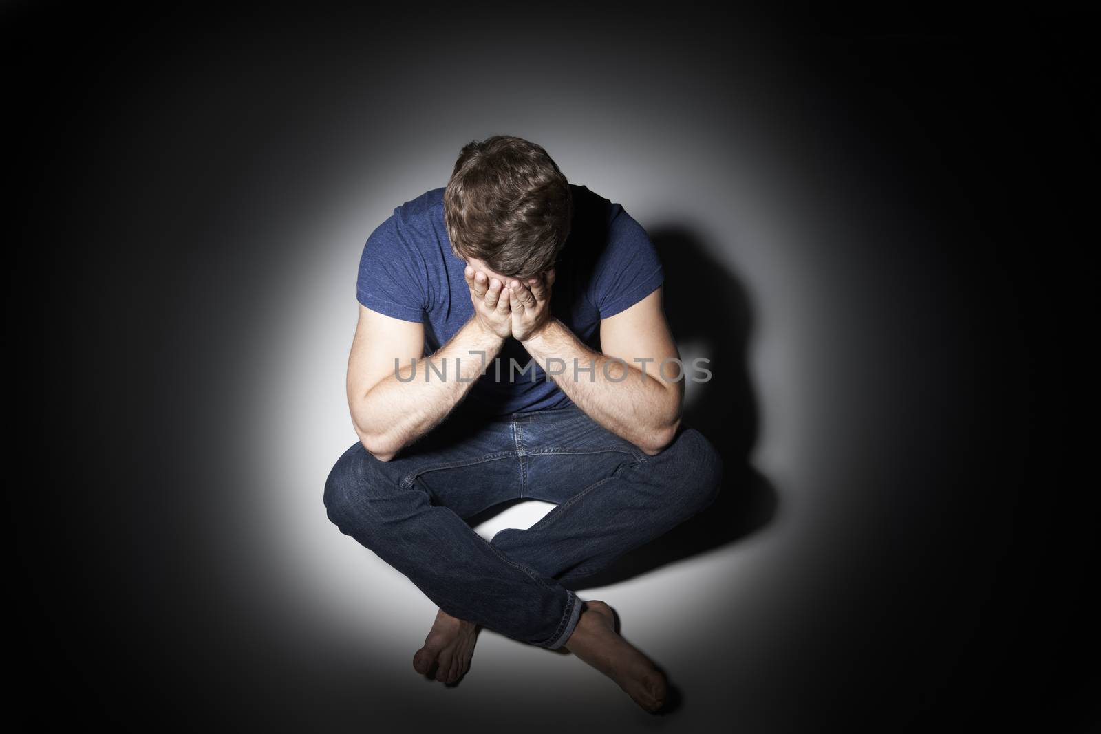 Unhappy Young Man Sitting In Pool Of Light by HWS