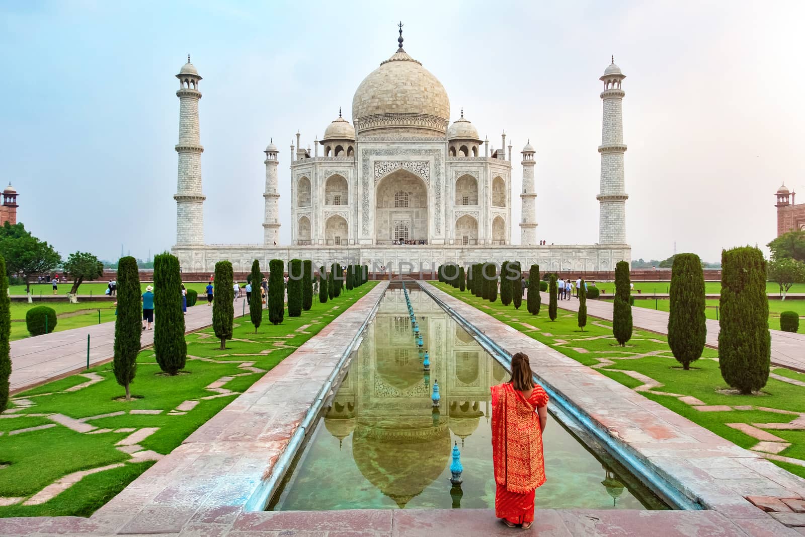 A woman standing front of Taj Mahal, an ivory-white marble mausoleum on the south bank of the Yamuna river in Agra, Uttar Pradesh, India. One of the seven wonders of the world.