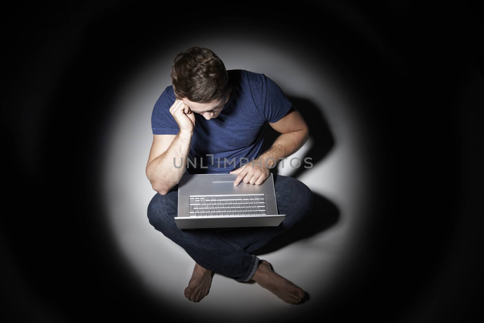 Young Man Using Laptop In Pool Of Light by HWS