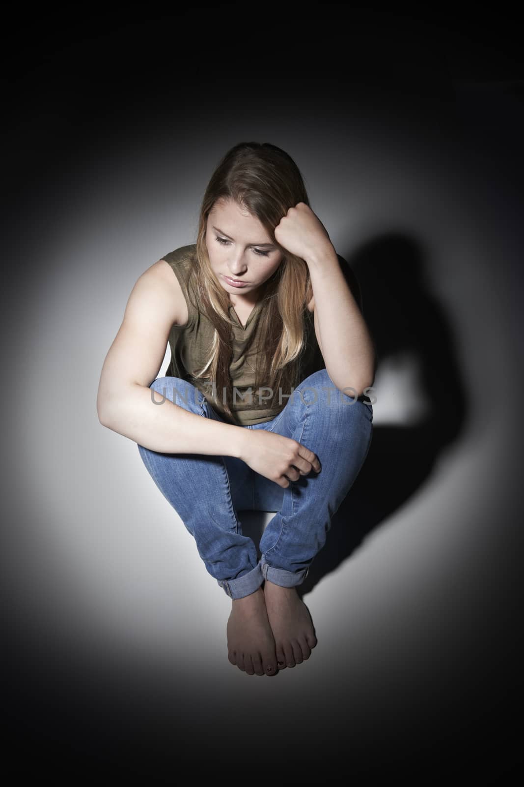 Unhappy Young Woman Sitting In Pool Of Light by HWS