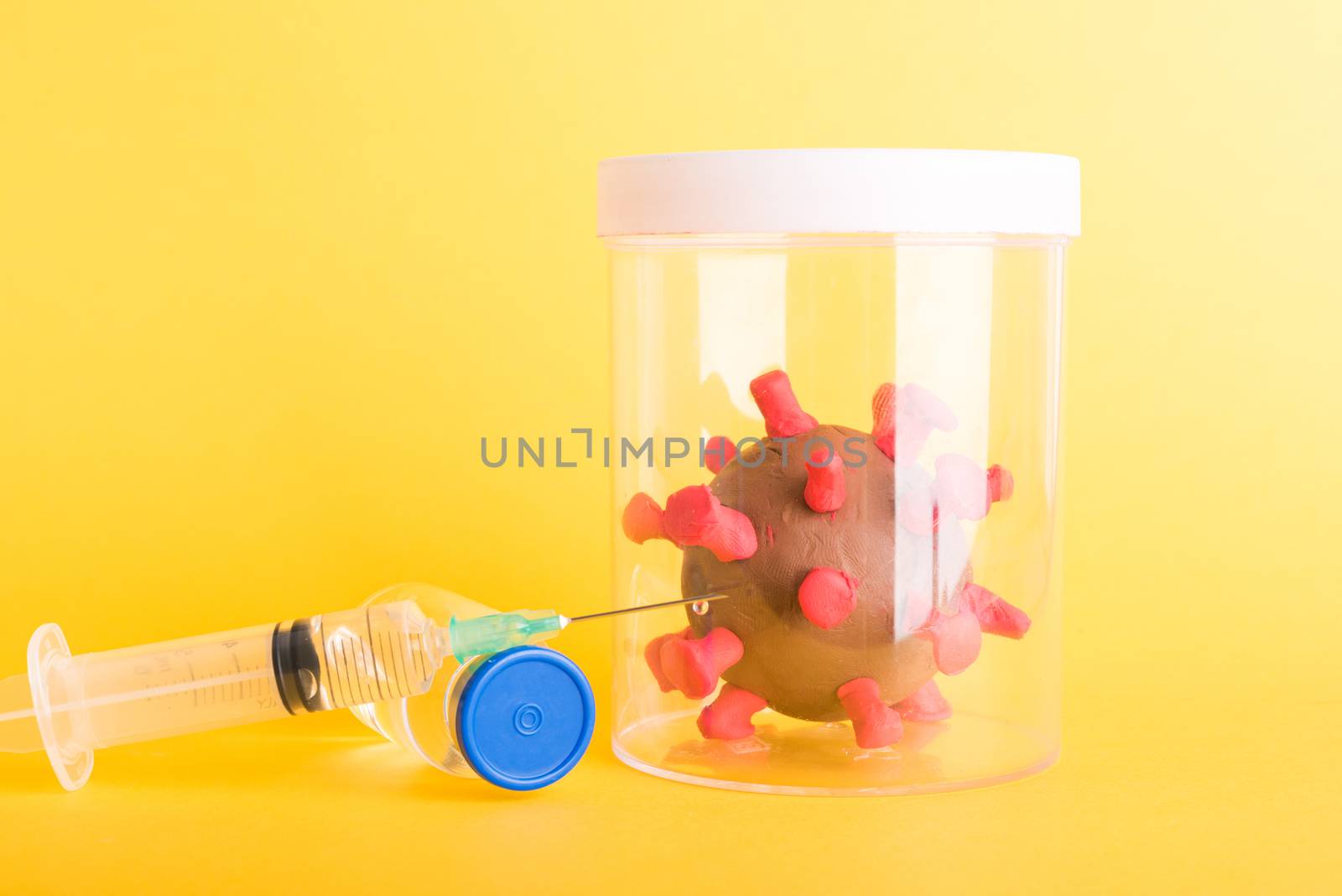 Imprison prevent plasticine disease cells virus in bottle, vaccine and syringe for research in lab of coronavirus outbreak and coronaviruses influenza flu, isolated on yellow, COVID-19 medical concept