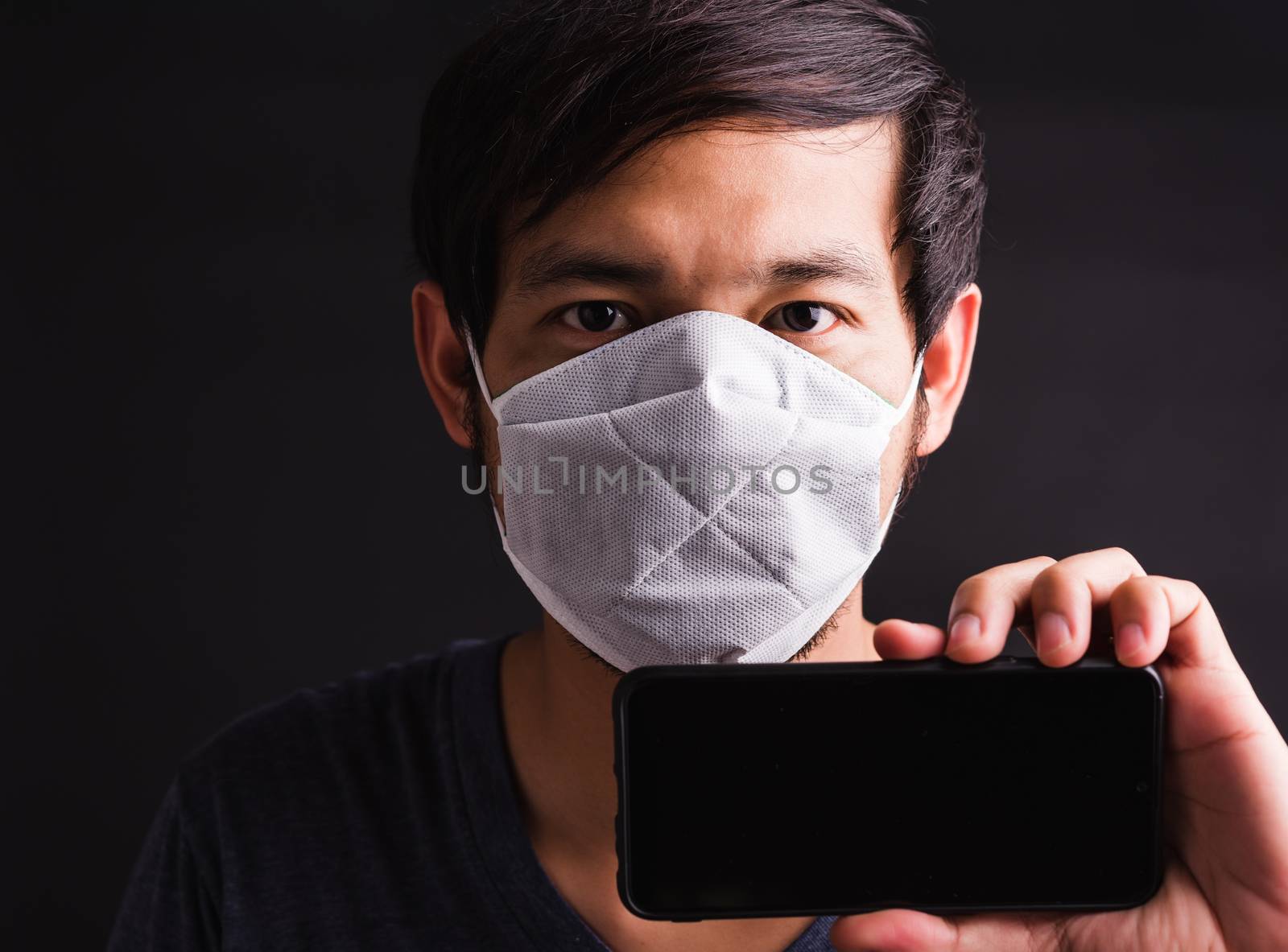 man wearing protective face mask fear in eye show mobile phone by Sorapop
