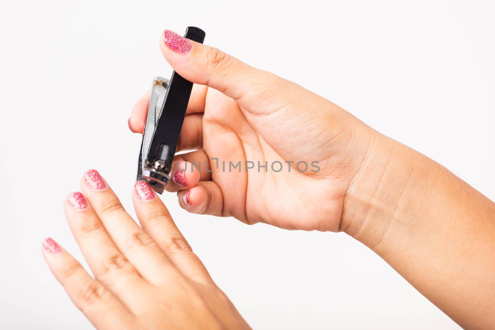 Close up young Asian woman have tool cutting nails fingernails on finger using a nail clipper. Female using tweezers by herself, studio shot isolated on white background, Healthcare concept