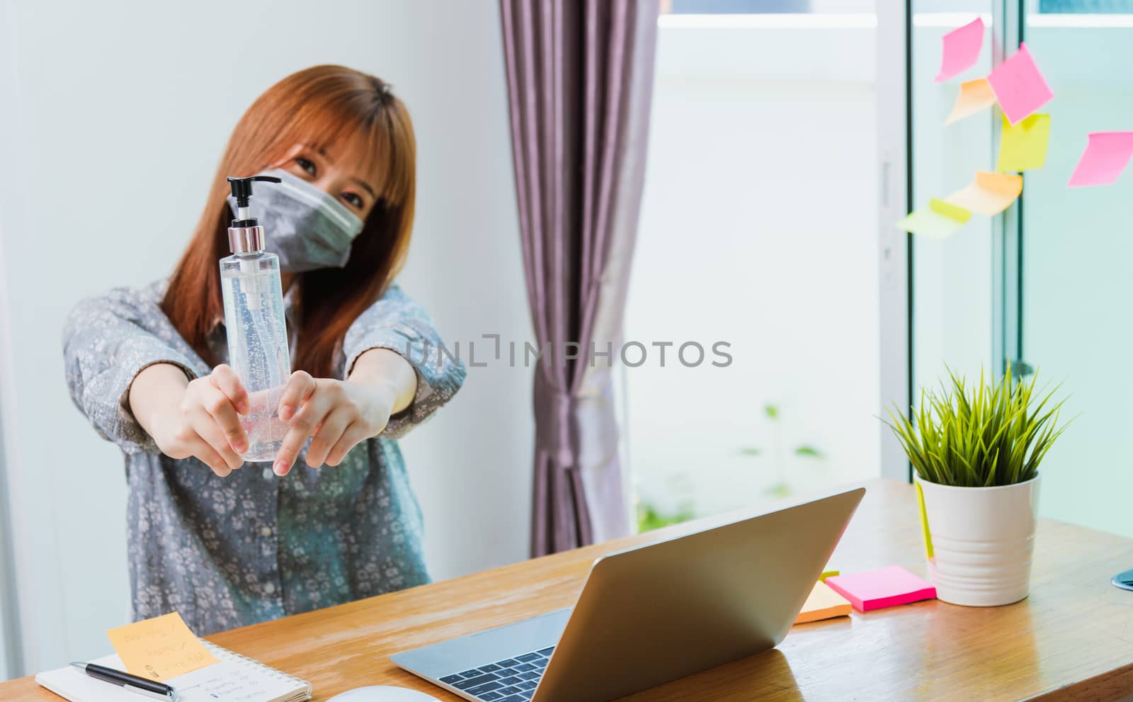 Work from home concept, Asian young business woman wearing face mask protective quarantines disease pandemic coronavirus or COVID-19 her show sanitizing gel with laptop computer at home office