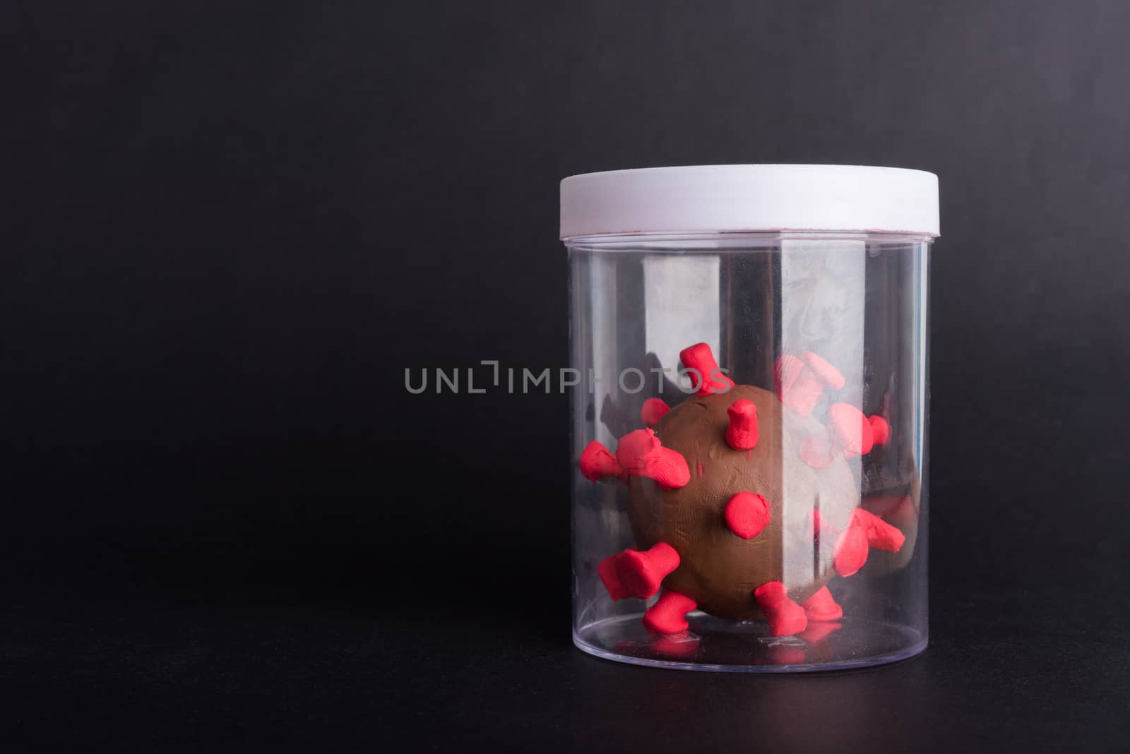 Imprison prevent plasticine disease cells virus in bottle for research in lab of coronavirus outbreak and coronaviruses influenza flu, studio shot isolated on black background, COVID-19 medical health