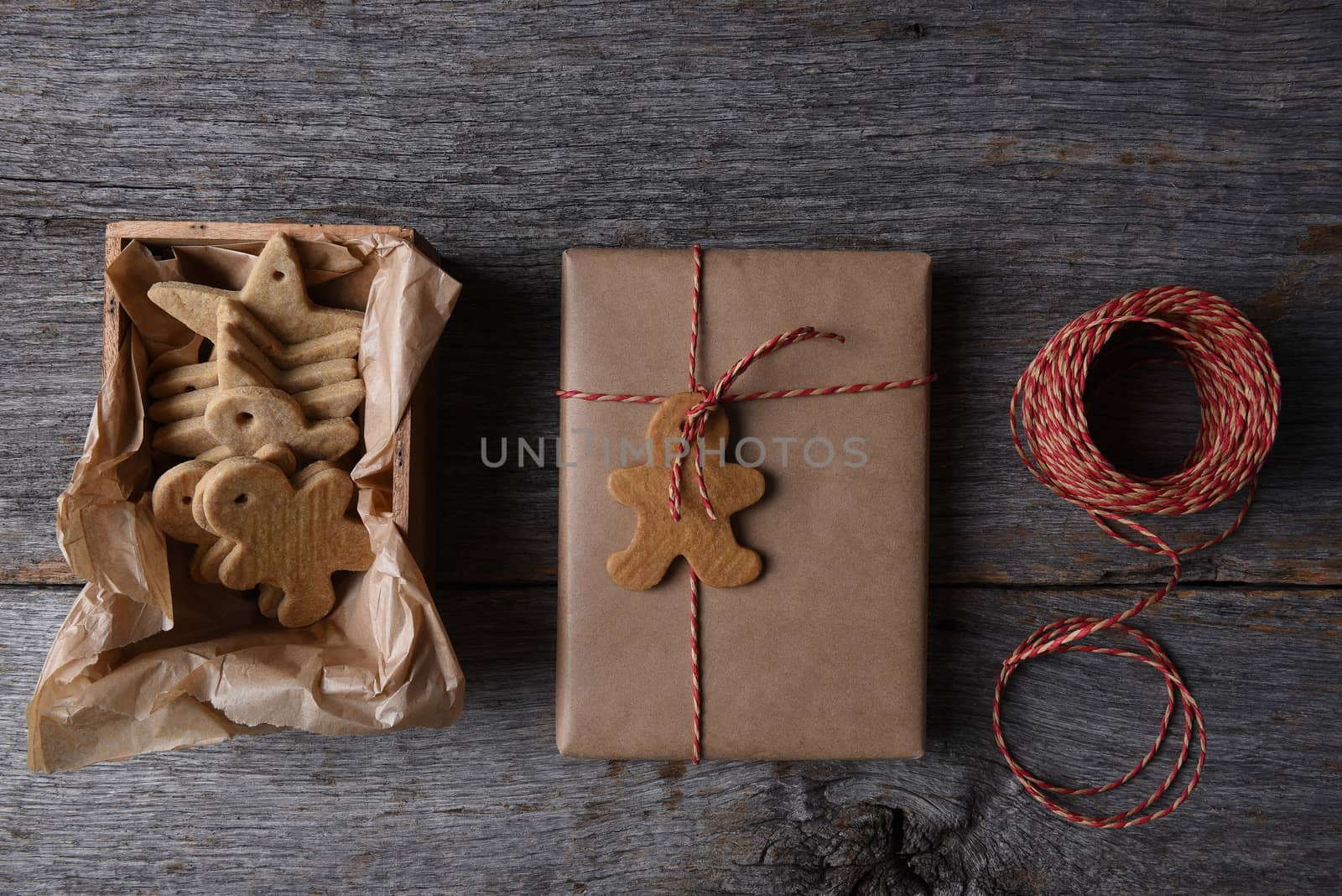 Top view of Christmas Presents with a box of Holiday Shaped Cookies on a rustic wood background.