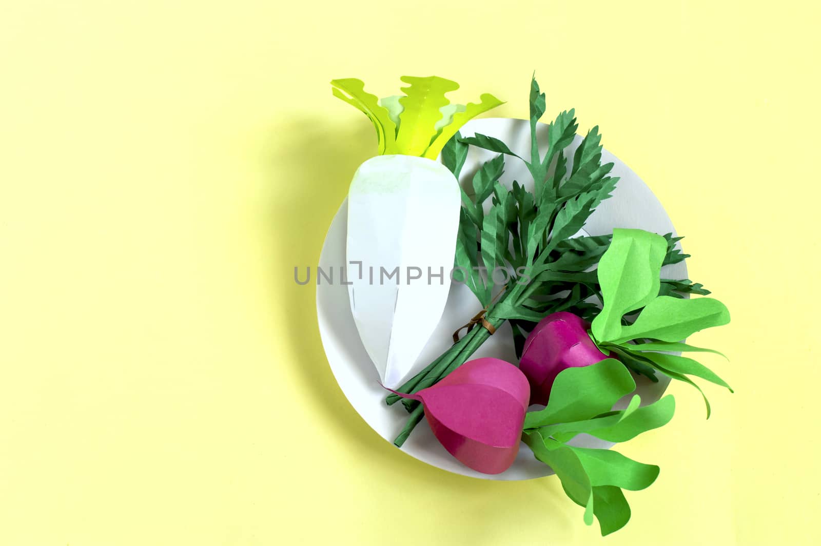 Colorful radish, parsley and daikon made from paper on yellow background. Real volumetric handmade paper objects. Paper art and craft