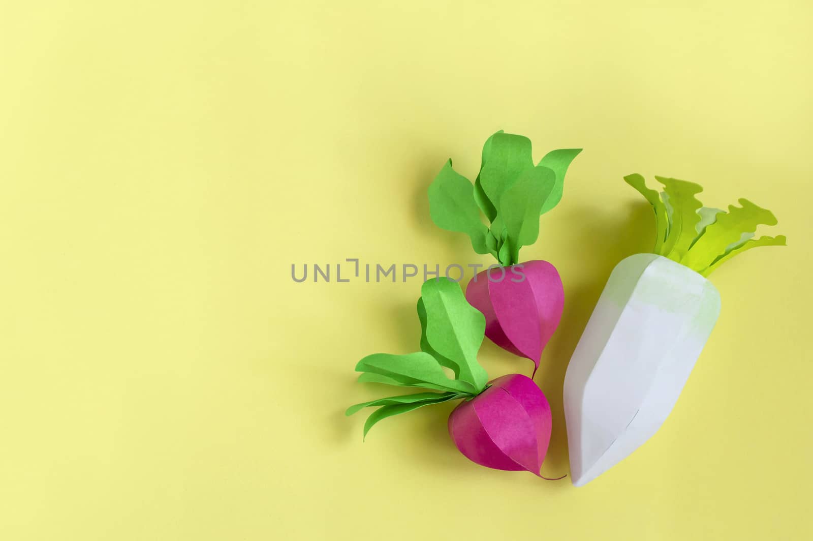 Colorful radish and daikon made from paper on yellow background. Real volumetric handmade paper objects. Paper art and craft