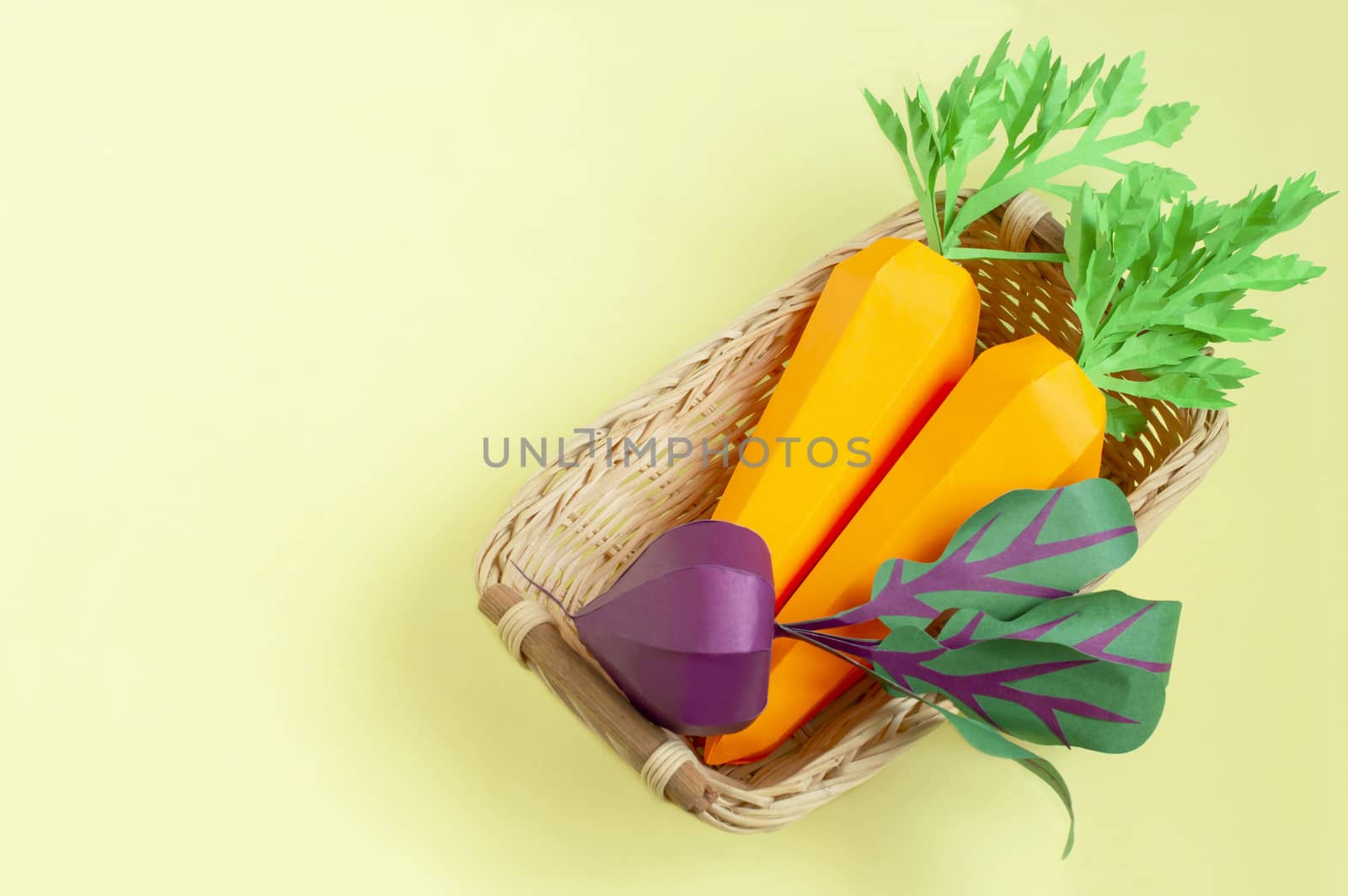 Colorful paper carrot and beet in wicker tray on yellow background. Real volumetric handmade paper objects. Paper art and craft