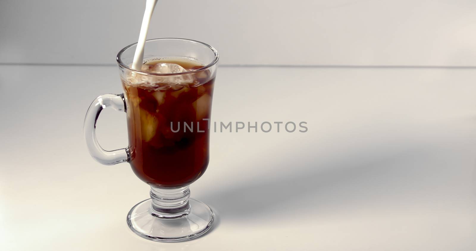 Pouring cream on an ice coffee cup on a white background