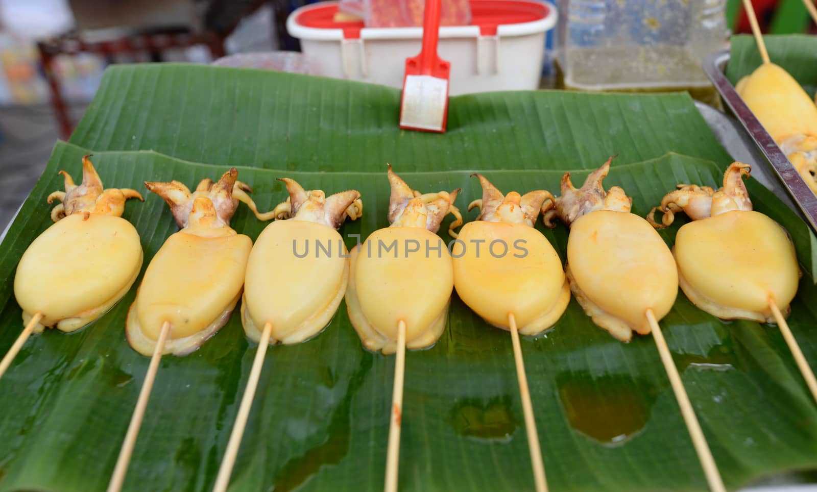 Squid carapace, skewers placed on a green banana leaf for sale