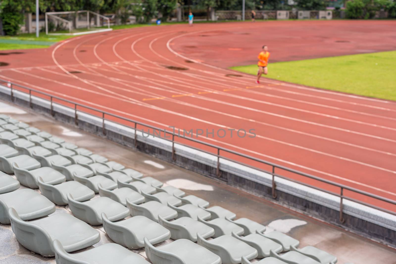 Selective focus on seats in a stadium with a man running in the background