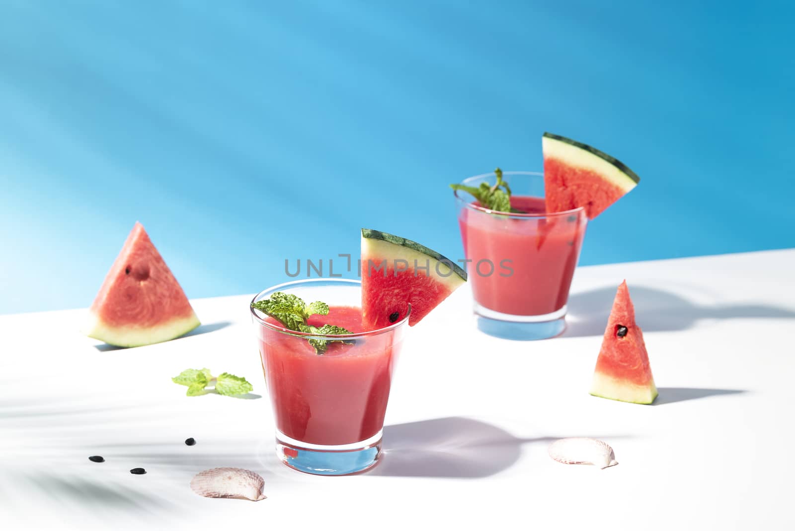 Fresh water melon juice and watermelon slice on blue background. summer drink.