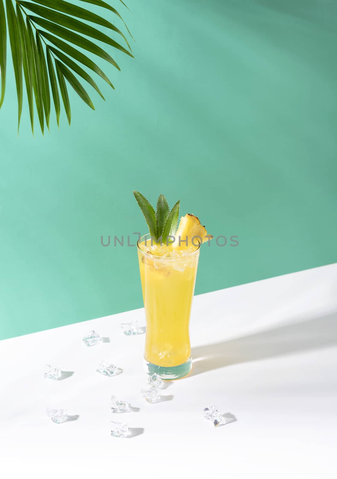 iced pineapple punch cocktail in glass on green background. summer drink.