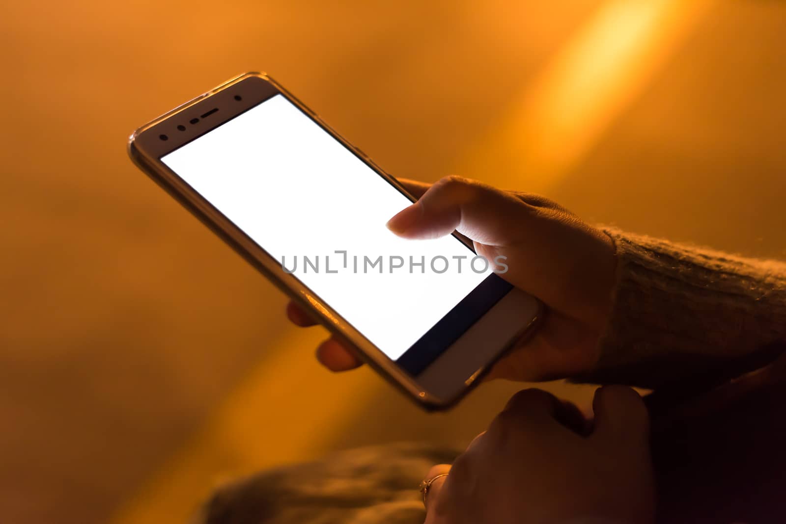 Girl holding a smartphone with a blank white screen at night