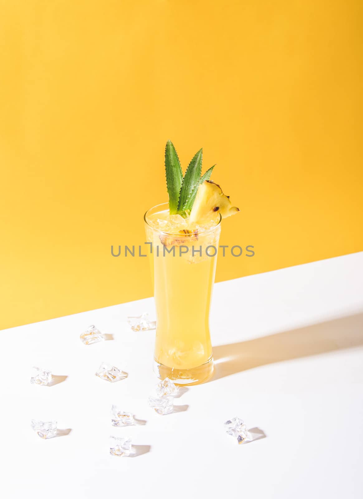 iced pineapple punch cocktail in glass on yellow background. summer drink.